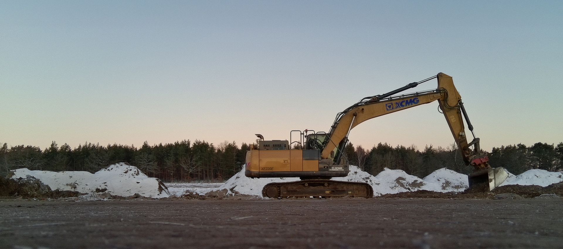 Ein großer Bagger befindet sich auf einer Schneeschicht.
